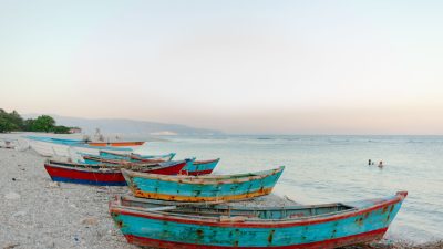 boats on beach near sea with swimming tourists