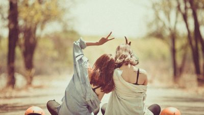 young women sitting together on road in park