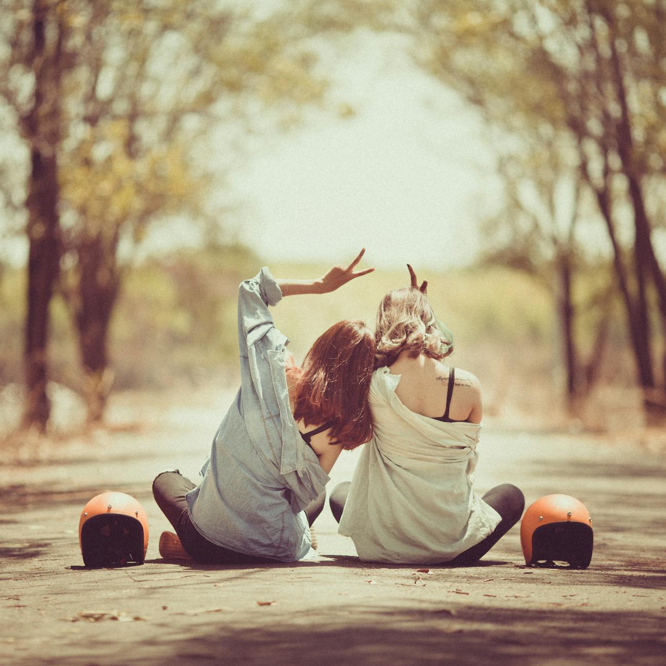 young women sitting together on road in park