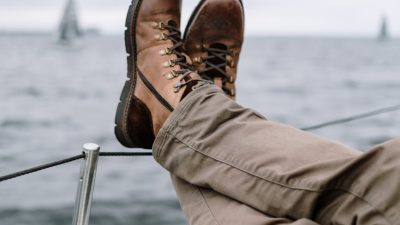 legs of a man leaning on the rope railing of a ship