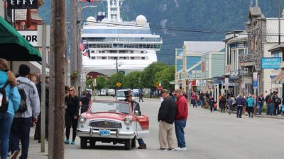 man in red shirt standing beside red car