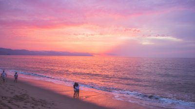 people standing on the beach during sunset