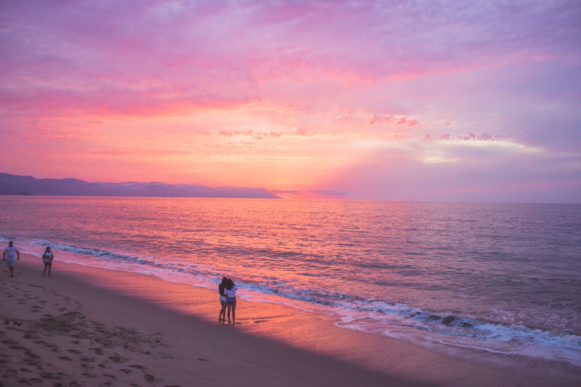 people standing on the beach during sunset