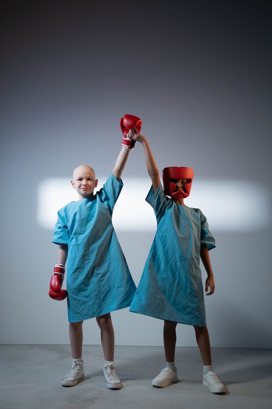 young boys in hospital gowns wearing protective head hear and boxing gloves