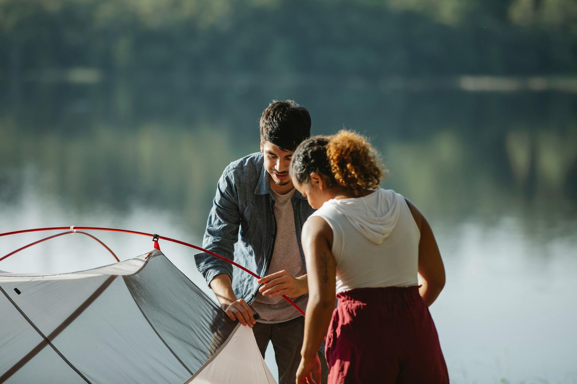 concentrated traveling couple with tent near lake