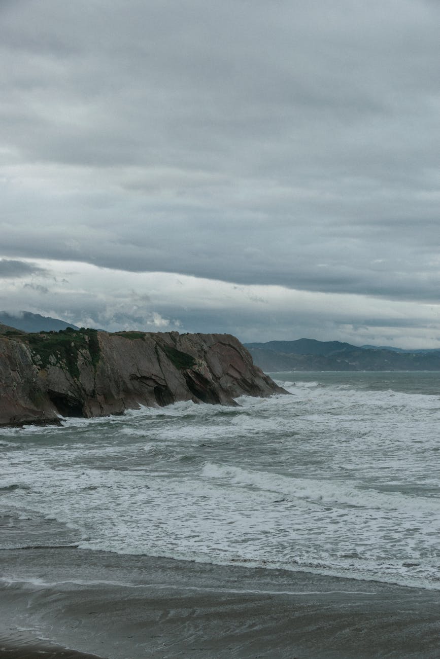 wavy foamy sea washing rocky cliff and beach