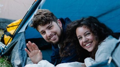 happy young couple smiling in tent in nature