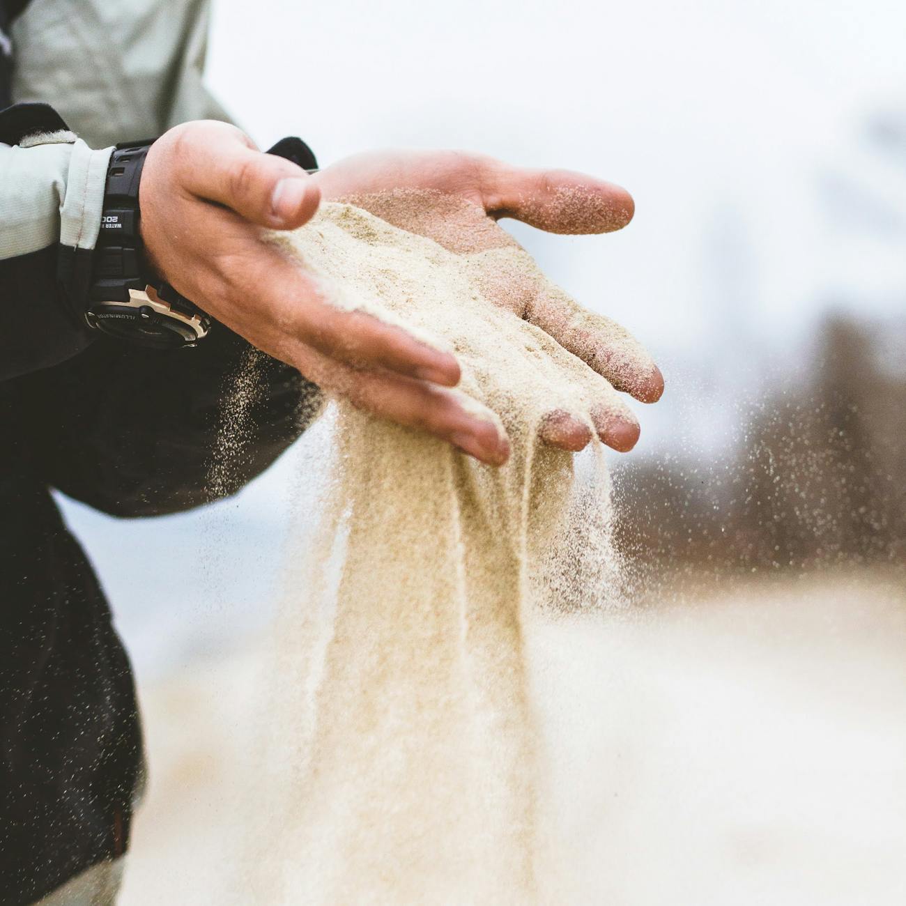 man pouring small pieces of sand on coat