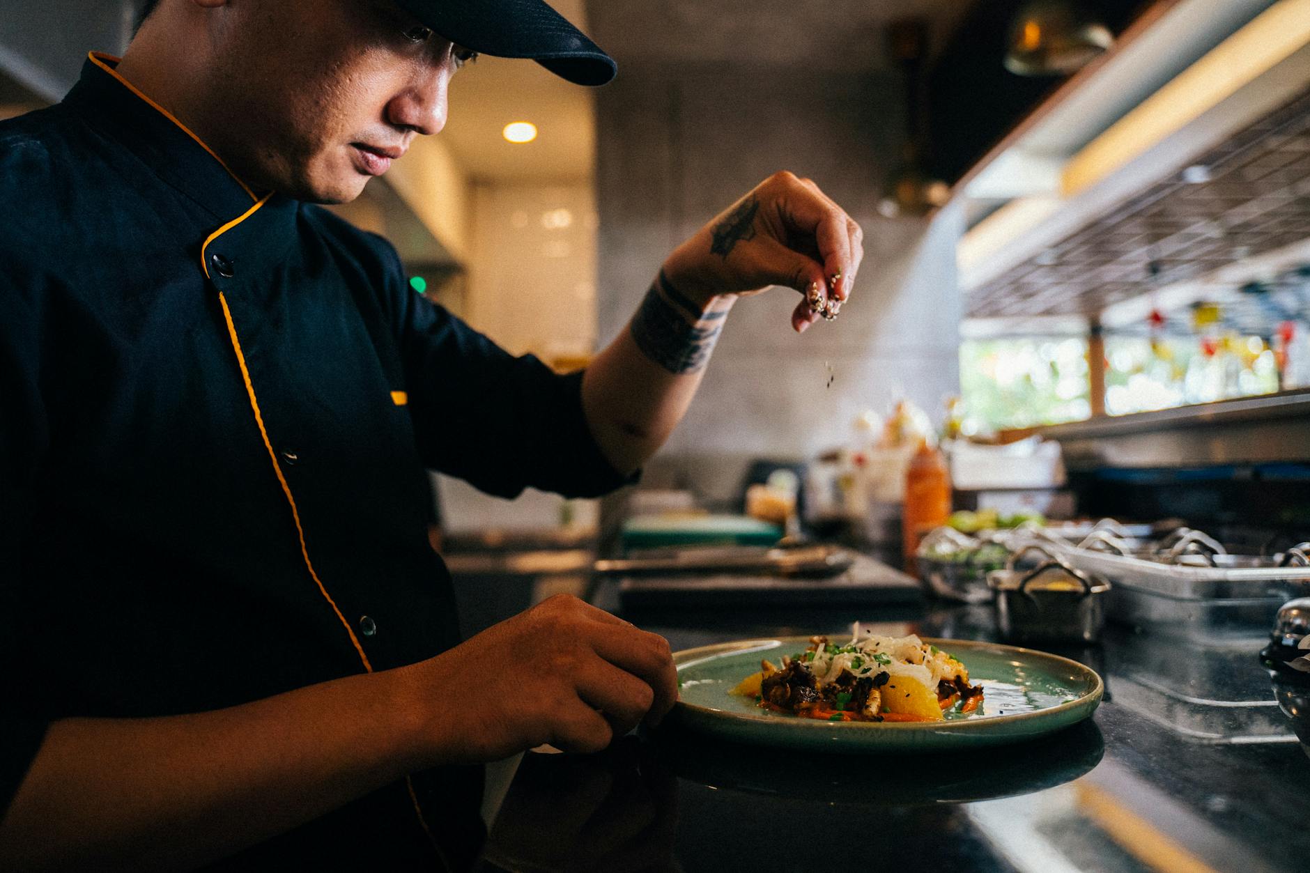 a chef sprinkling sesame seeds on a salad dish