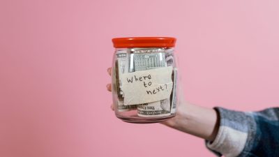 a person holding a glass jar with money