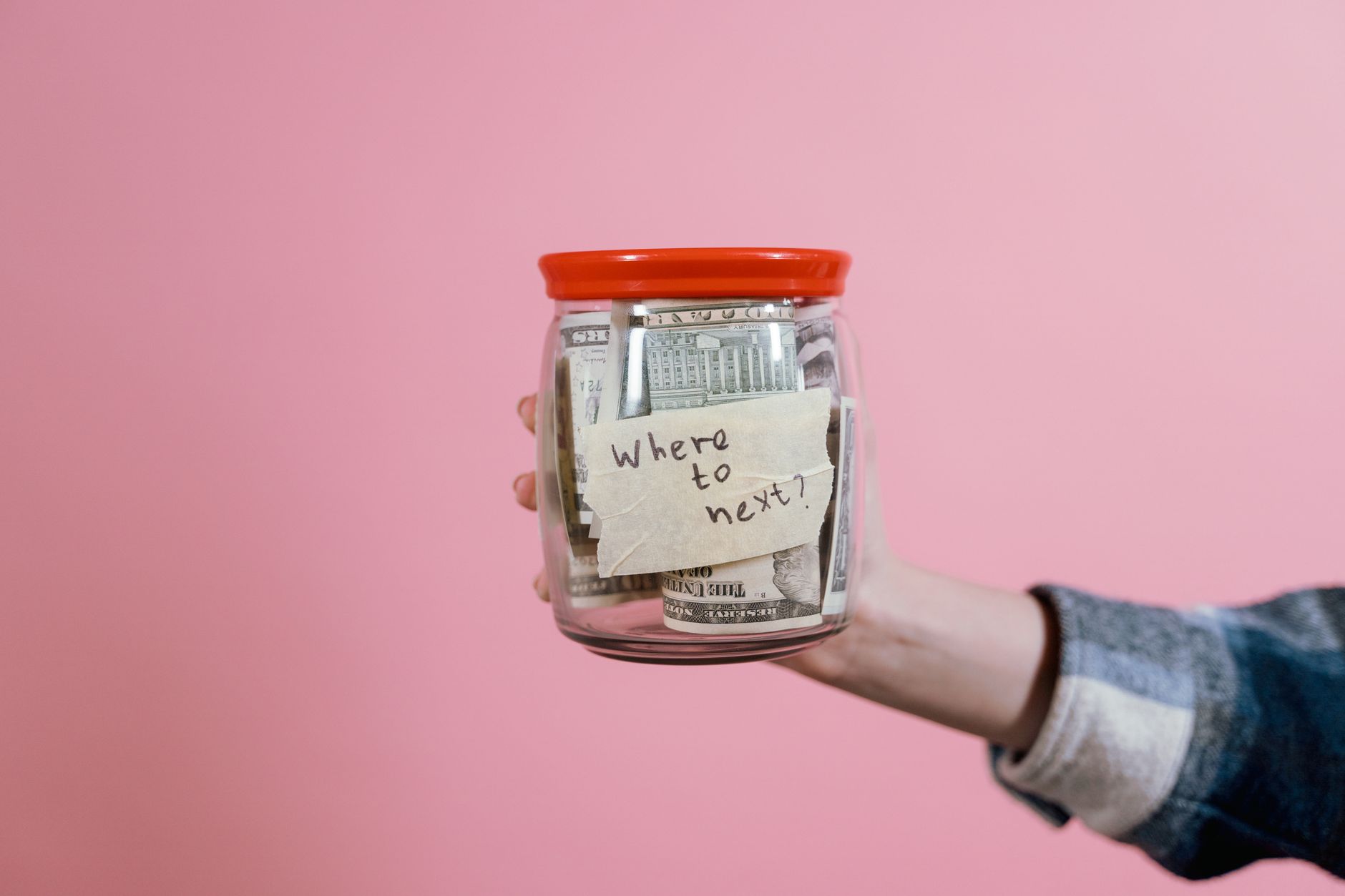 a person holding a glass jar with money