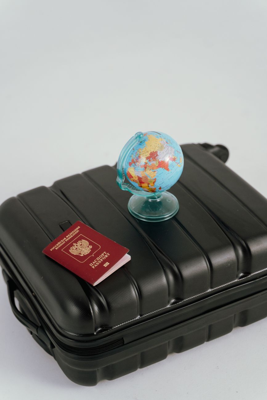 globe and passport on black luggage