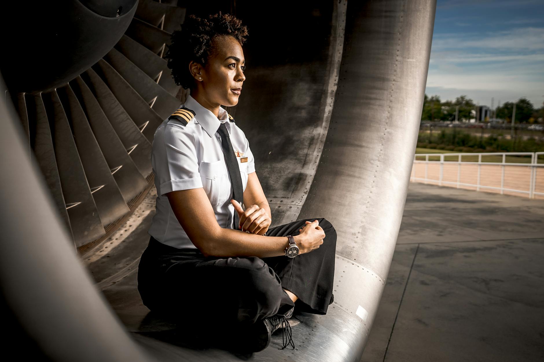 woman wearing uniform sitting beside an aircraft engine