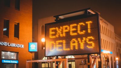 glowing signboard with inscription placed on city road in evening time