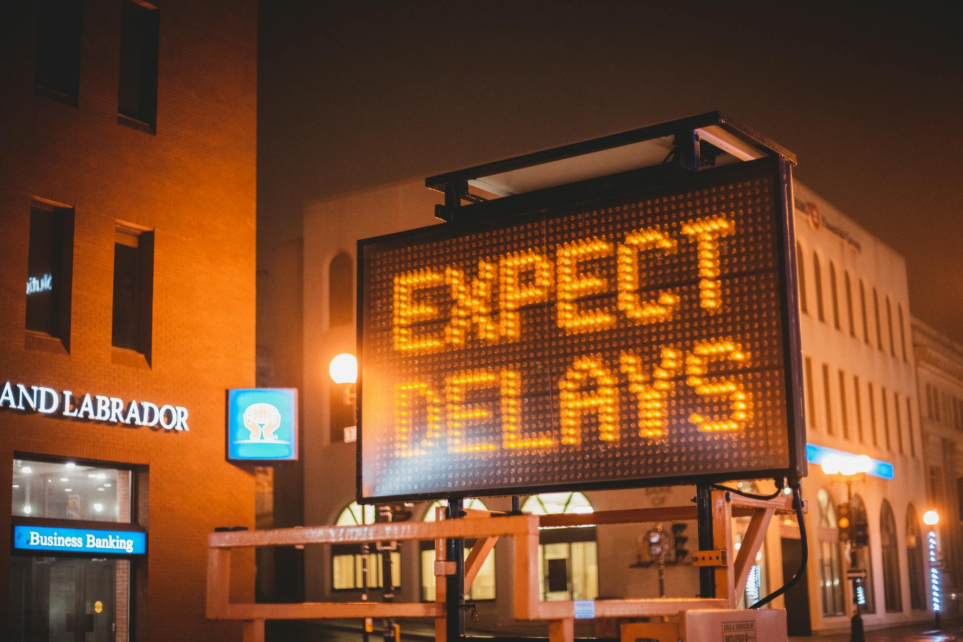 glowing signboard with inscription placed on city road in evening time