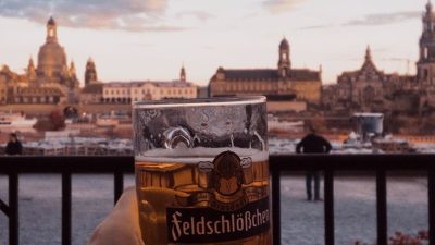 a person holding a clear drinking glass with beer