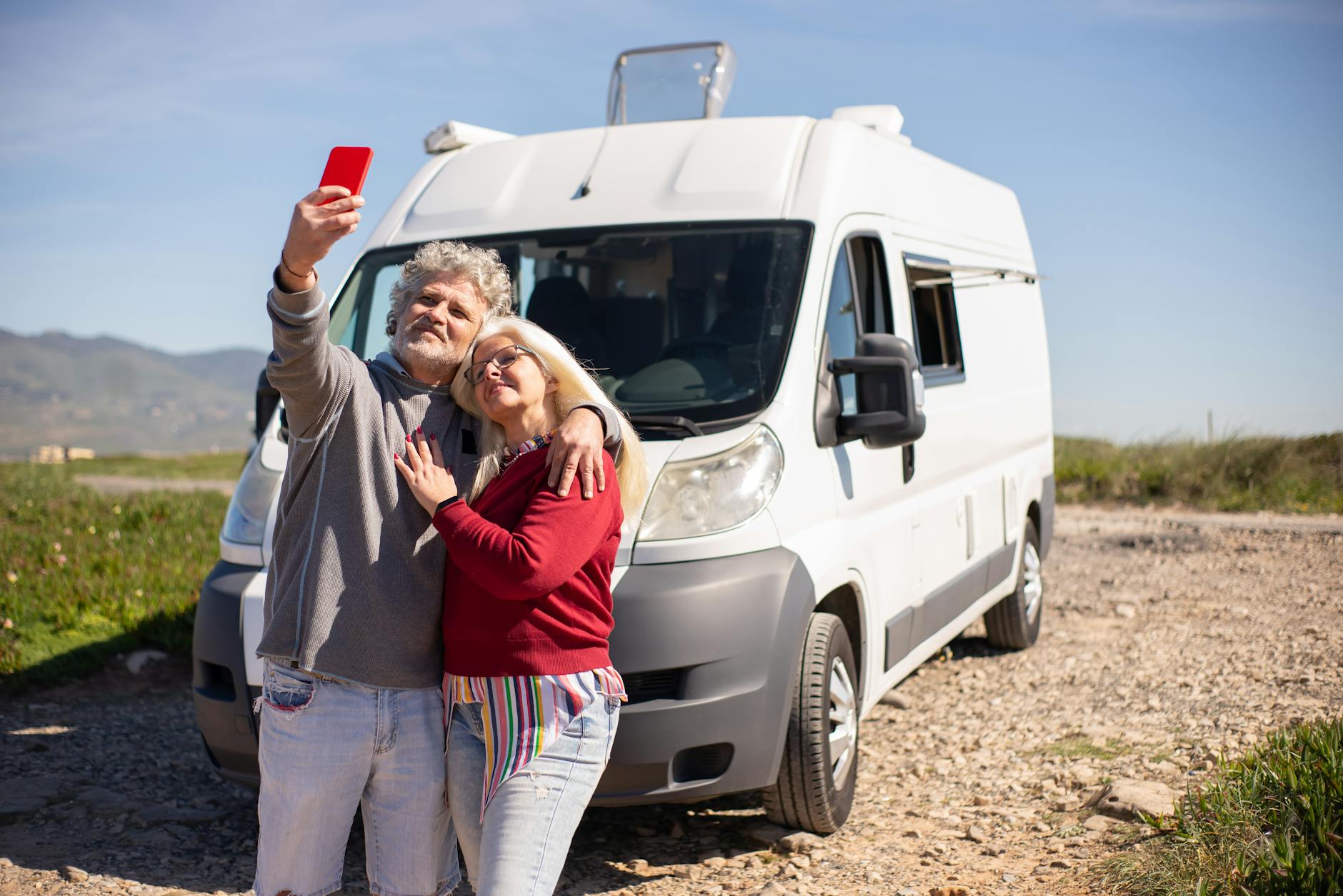 an elderly couple taking a selfie beside their recreational vehicle
