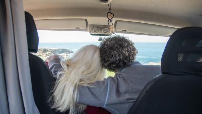 back view of a couple sitting in a campervan and hugging
