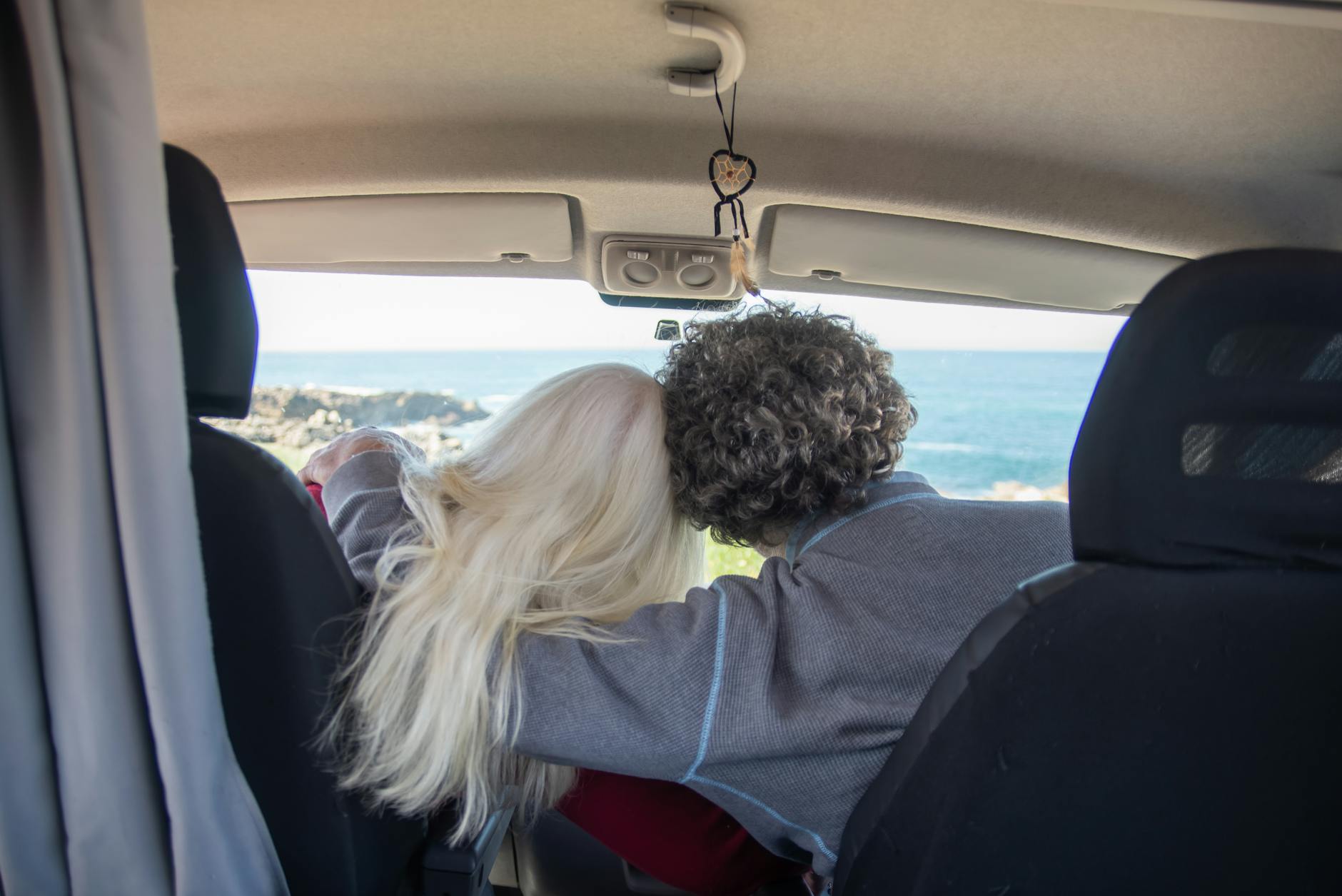 back view of a couple sitting in a campervan and hugging