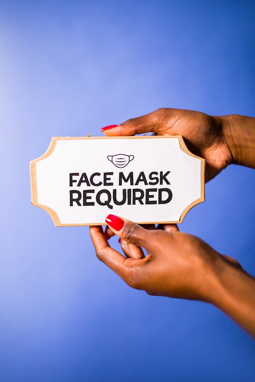woman holding a white sign with a text about face masks