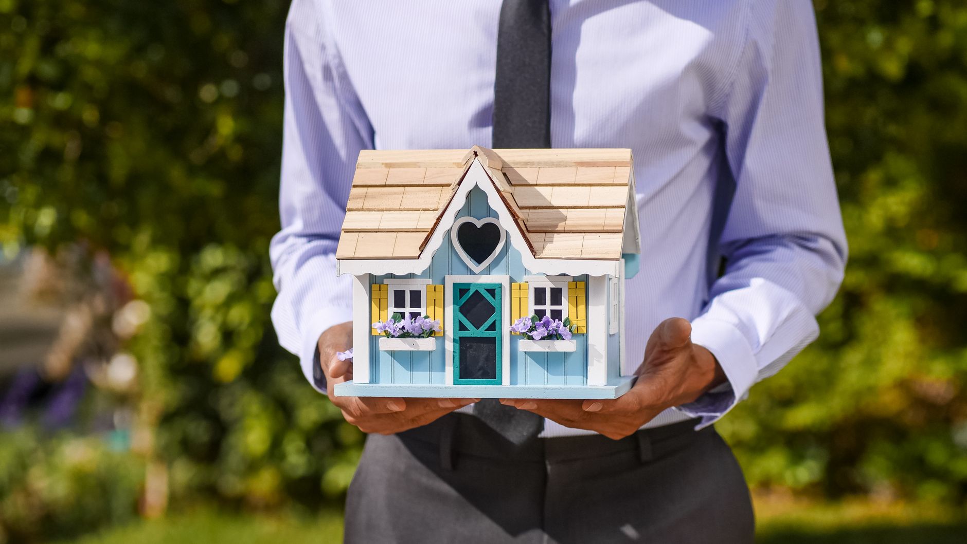 person holding miniature wooden house