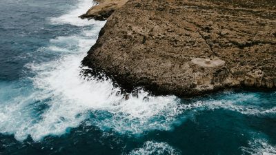 brown rock formation beside body of water