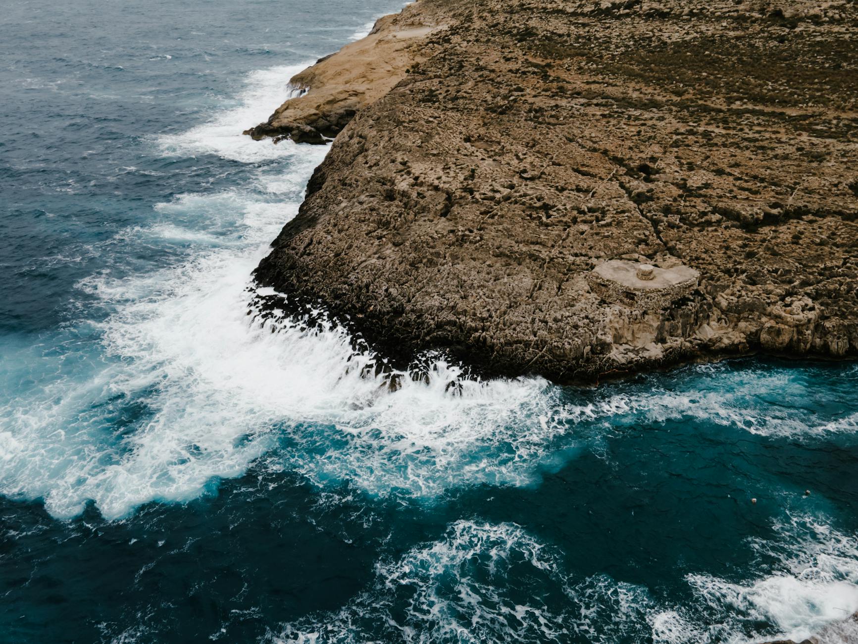 brown rock formation beside body of water