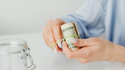 close up shot of a person using rubber band to tie up the paper money