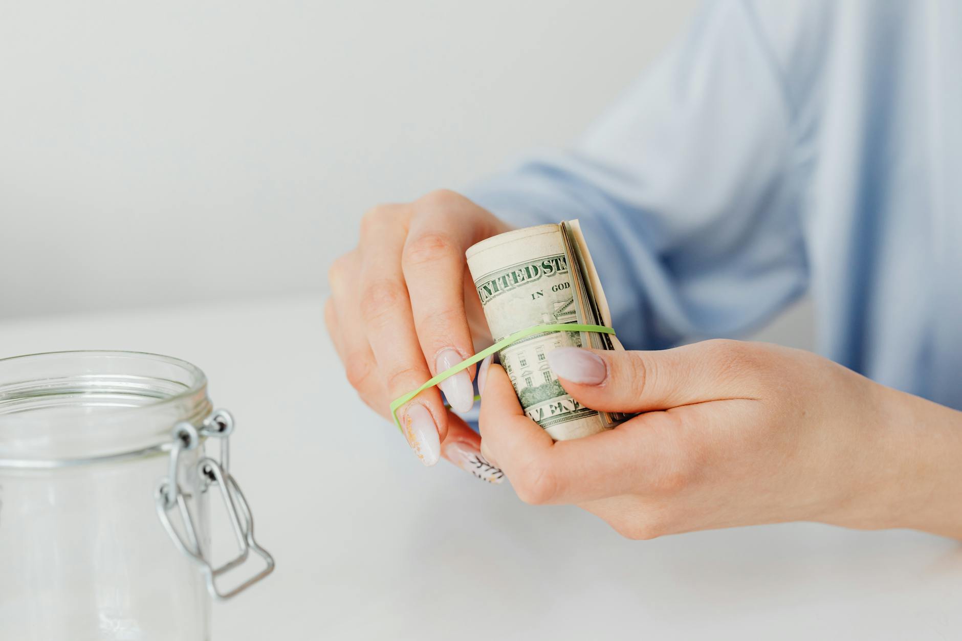 close up shot of a person using rubber band to tie up the paper money