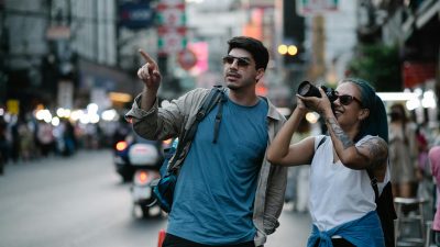 a woman beside a man taking photos using a camera