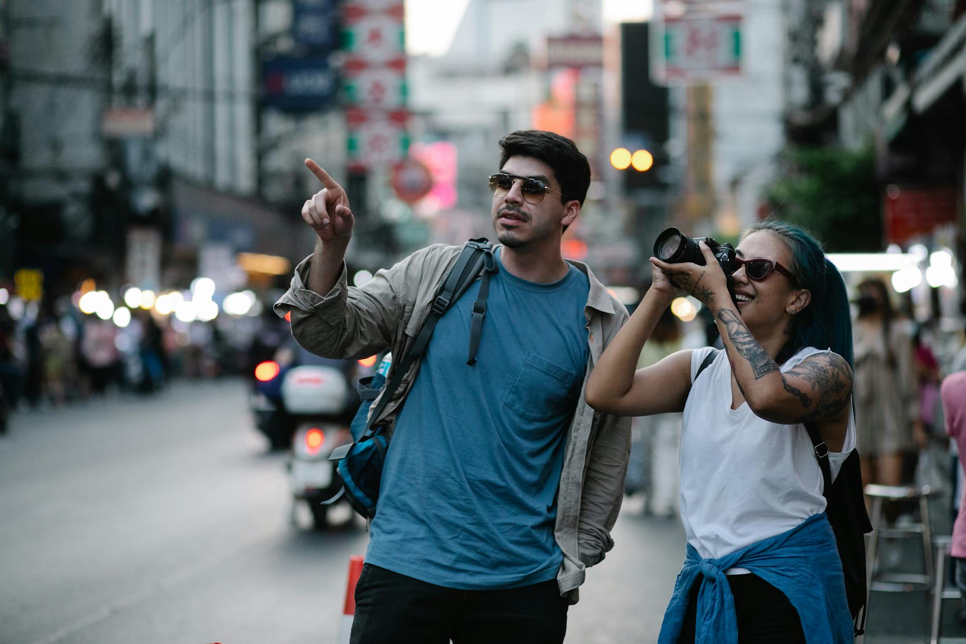 a woman beside a man taking photos using a camera