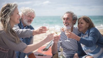 gray haired people toasting wine glasses