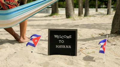 a welcome to havana sign on sand between cuban flags