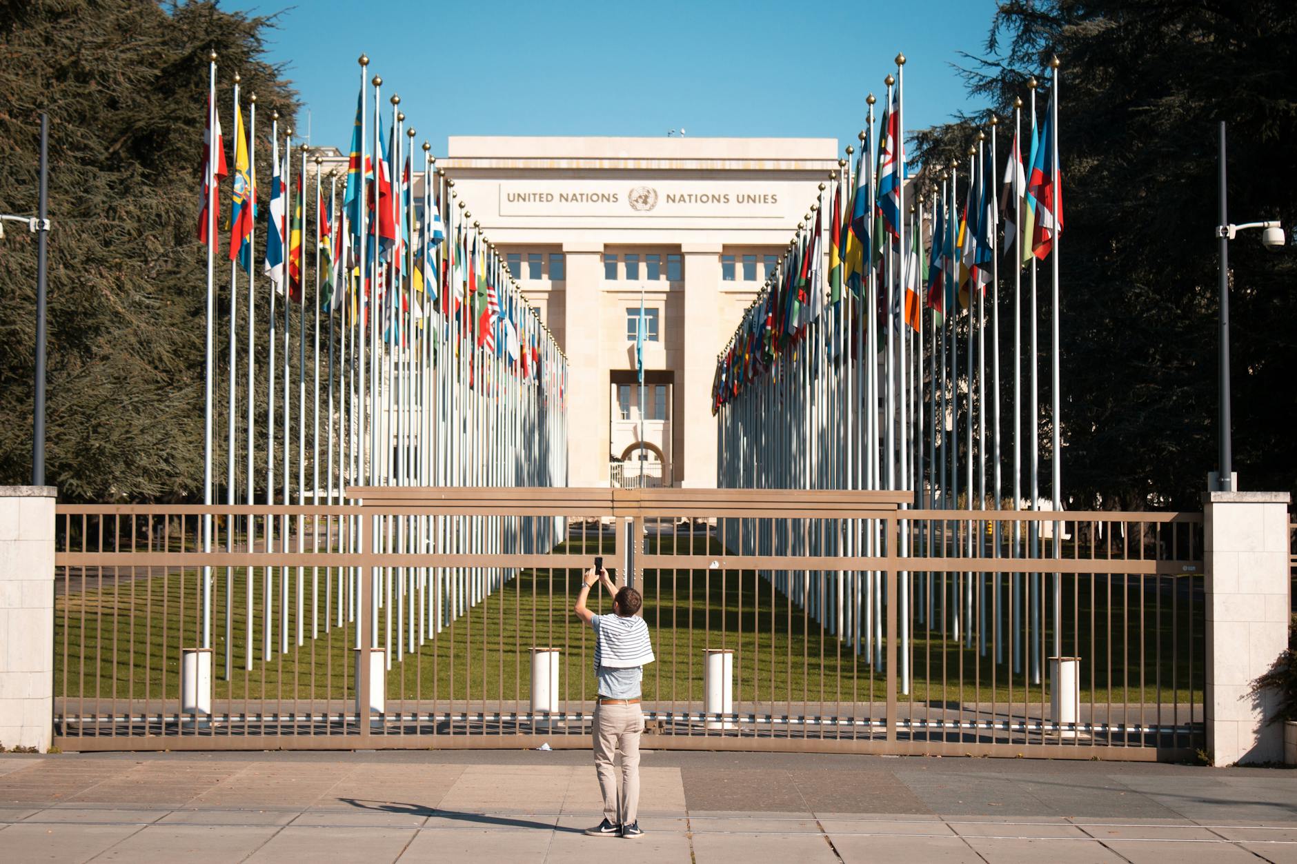 man photographing flags in front of government building