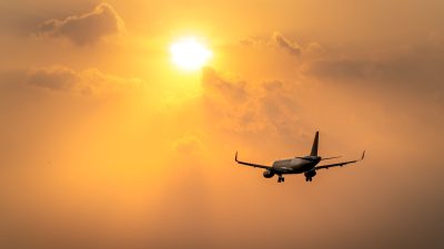 airplane flying under the bright sun
