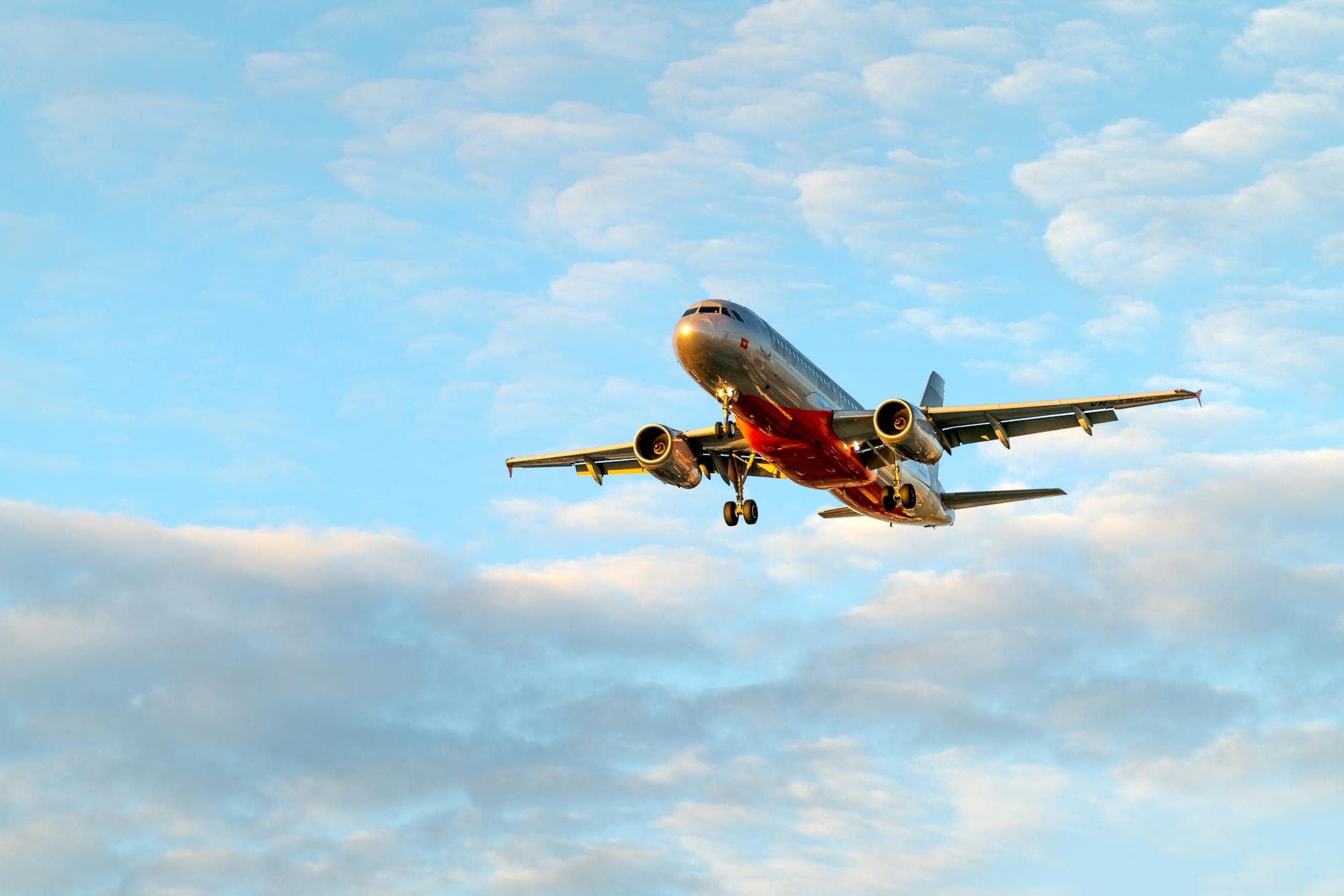 low angle shot of an airplane flying under cloudy sky