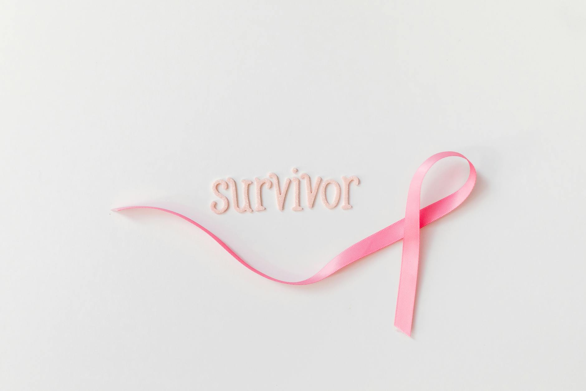 pink ribbon beside letters on a white surface