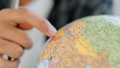 close up of a person pointing at a globe