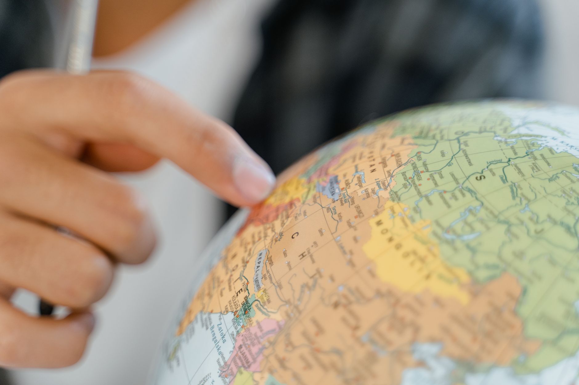 close up of a person pointing at a globe