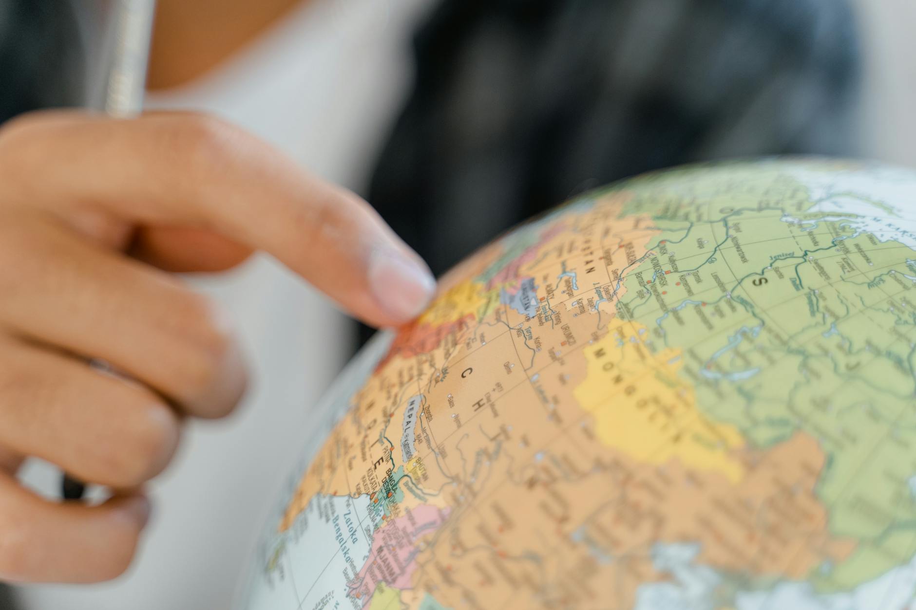 close up of a person pointing at a globe