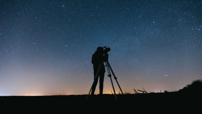 silhouette of person standing on a field under starry night