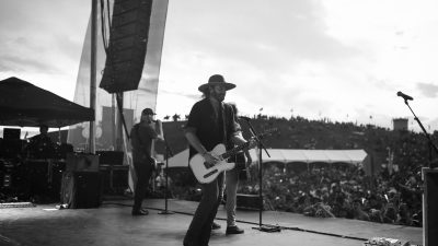 man in black hat playing guitar on stage
