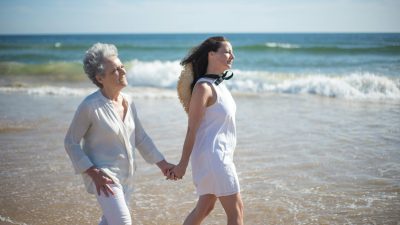 mother and daughter holding hands while walking at the beach