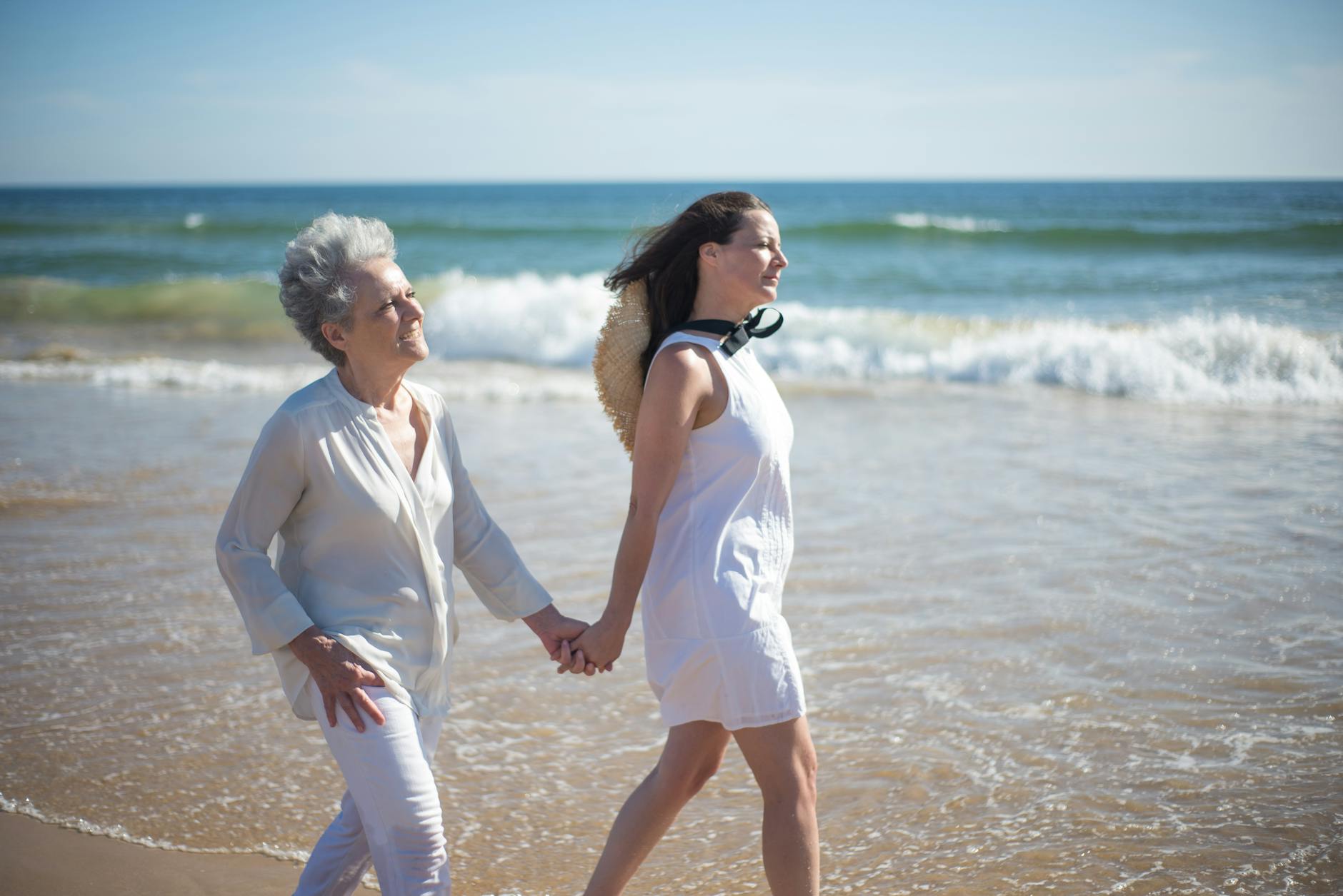 mother and daughter holding hands while walking at the beach