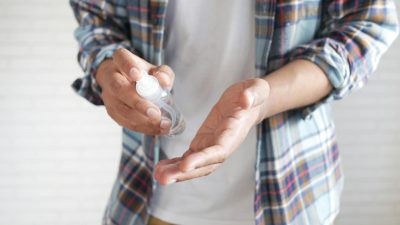person spraying alcohol on his hand