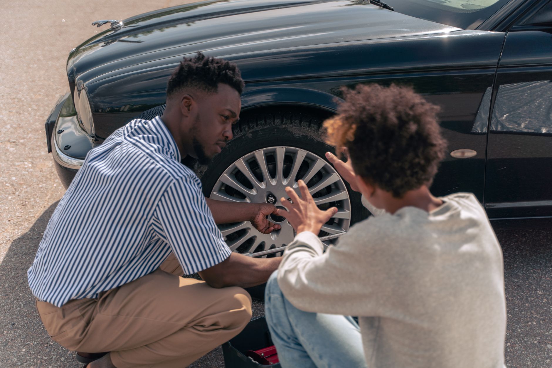 man in white and black stripe dress shirt sitting on car