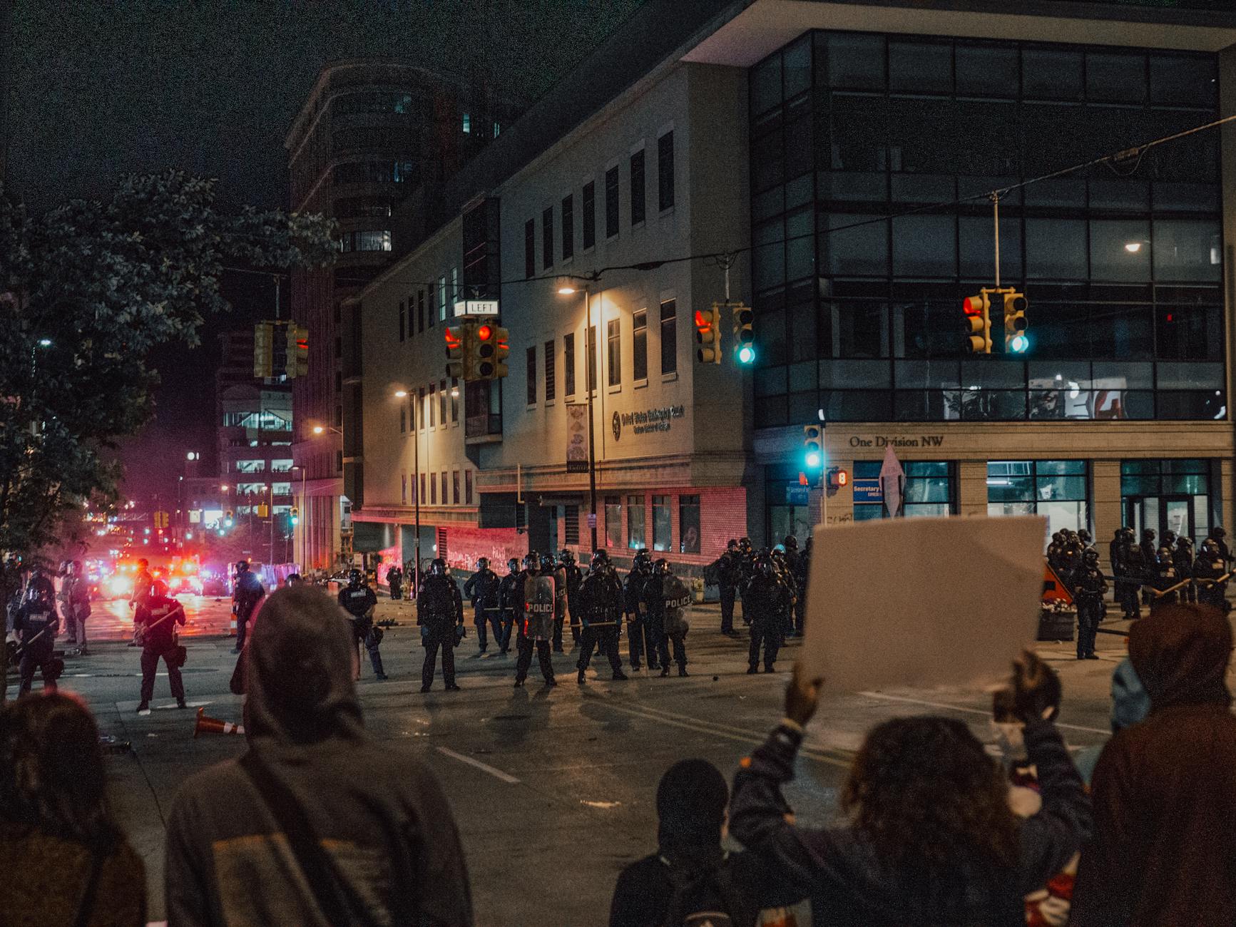 demonstrators with protest signs facing police officers